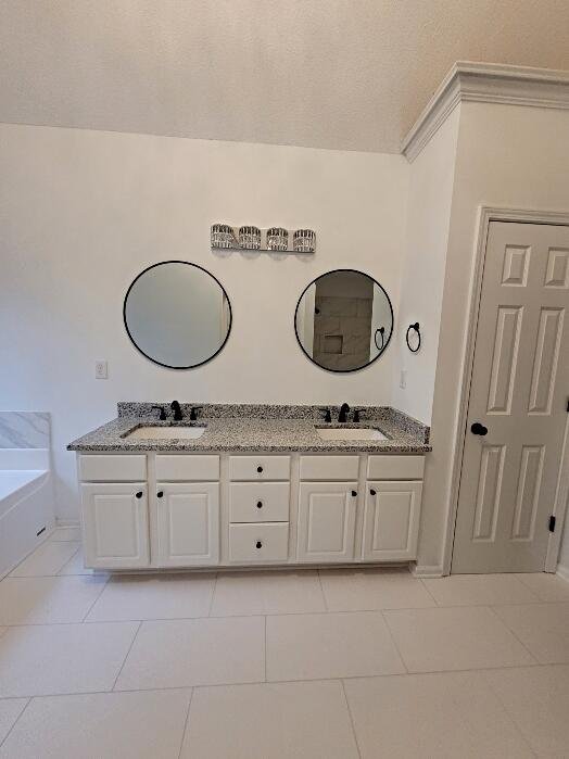 Bright white bathroom remodel in Cullman AL with double vanity, granite countertops, round mirrors, and large format tile floor