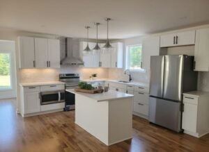 Bright kitchen remodel in Cullman AL with white cabinets, island, stainless appliances, and hardwood flooring installed by Hunter’s Ridge Construction.