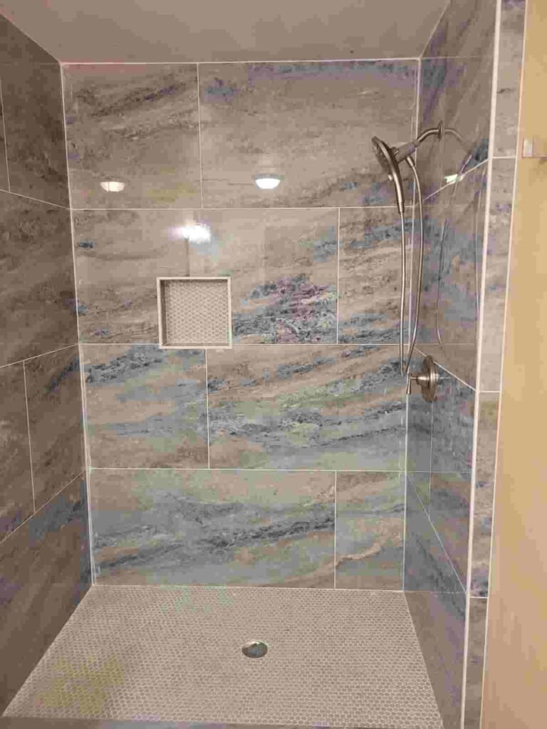 After: finished walk in shower with large format tile, niche, and modern fixtures