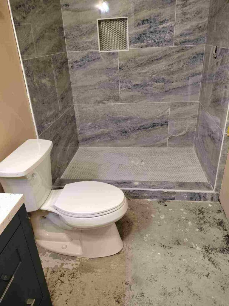 Bathroom remodel in progress with tile shower and unfinished flooring