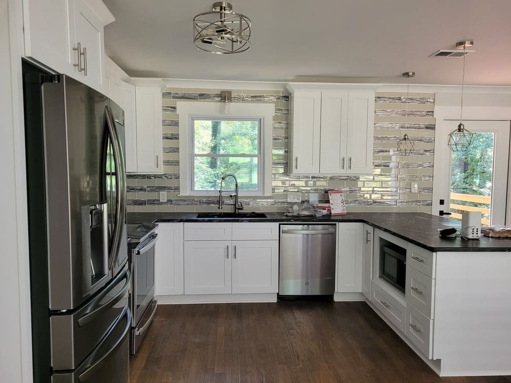 Finished kitchen with stainless appliances, white cabinets, and tile backsplash