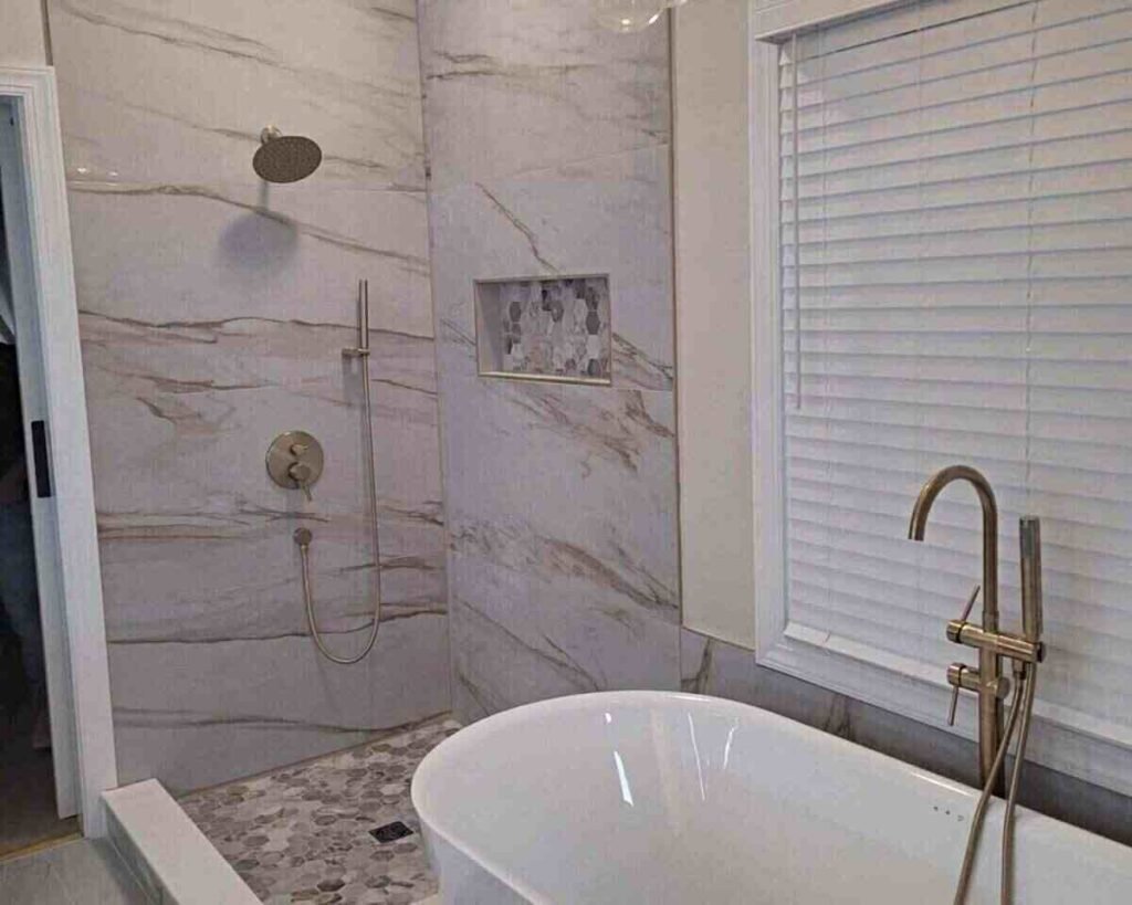 Finished bathroom remodel in Mountain Brook 35223 with freestanding tub, marble-look tile, and brass fixtures